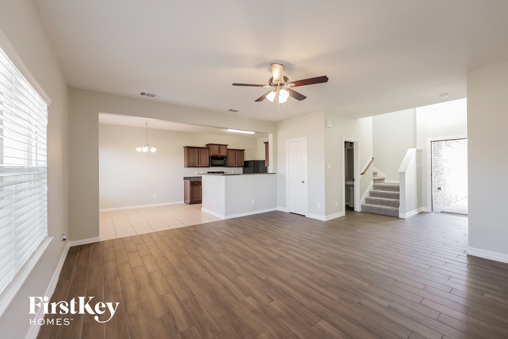 A spacious living room with wooden floors and a ceiling fan.