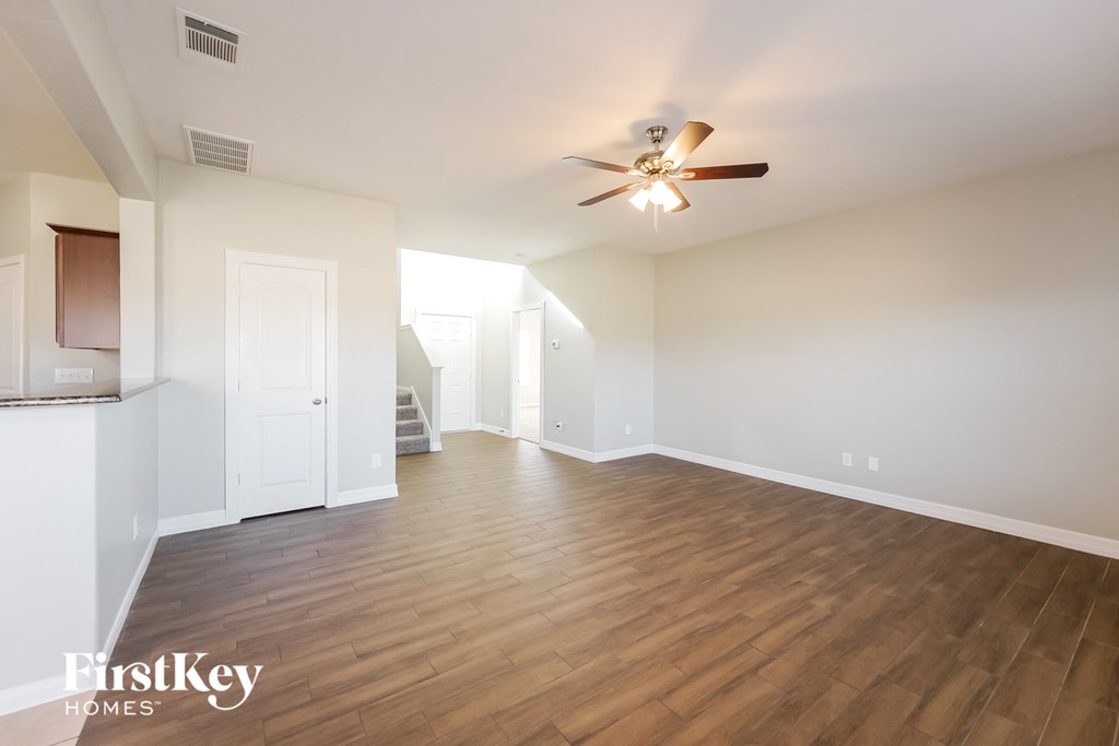 A spacious room with wooden flooring and a ceiling fan.