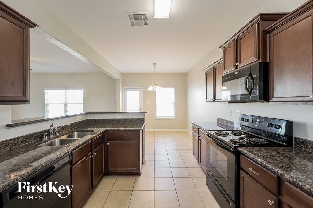 A kitchen with brown cabinets and a black stove top oven.