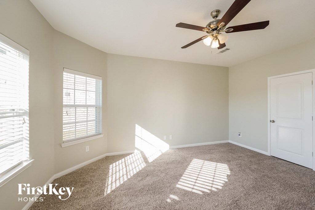 A room with a carpeted floor and a ceiling fan.