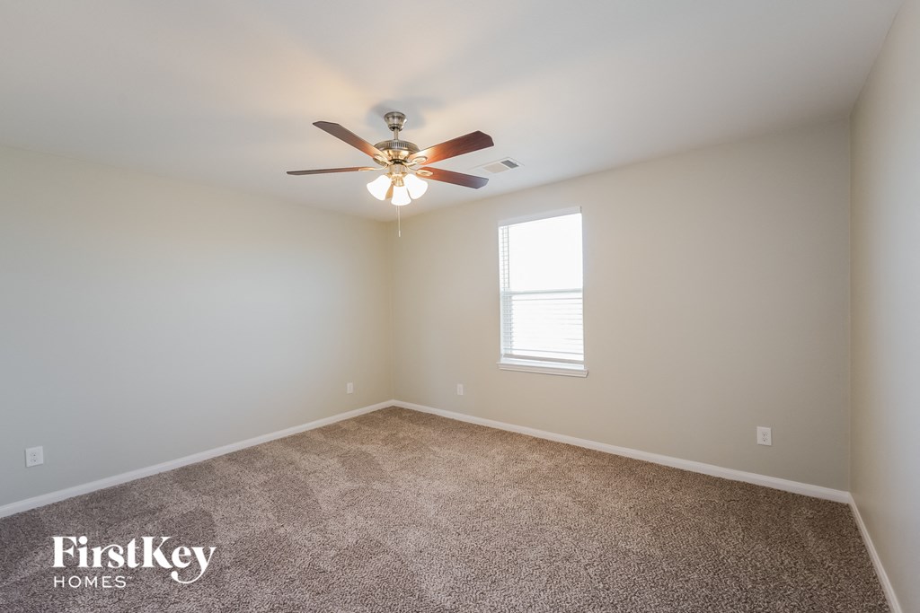 A room with a carpet floor and a ceiling fan.