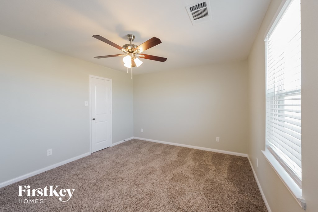 A room with a carpet floor and a ceiling fan.