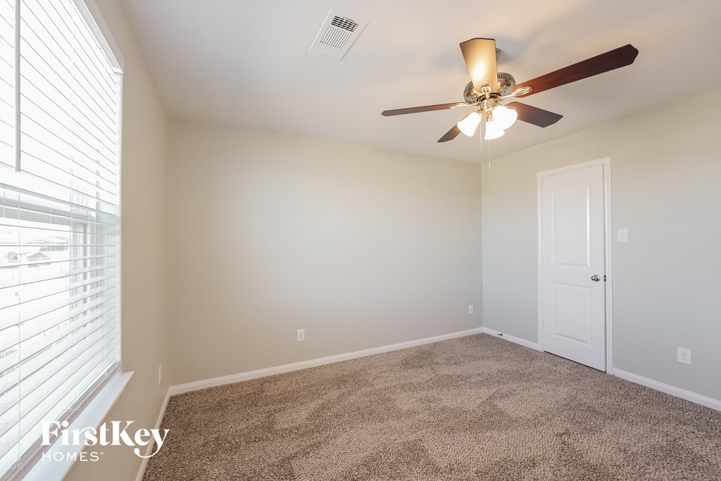 A room with a ceiling fan and a carpeted floor.