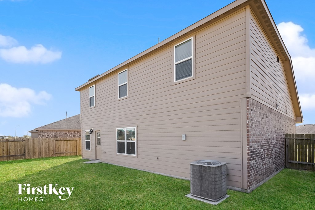A beige house with a brown fence and a brick pillar.