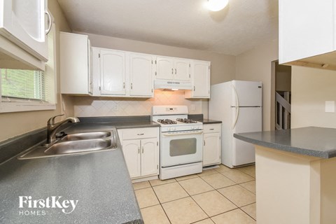 A kitchen with white cabinets and a grey counter top.