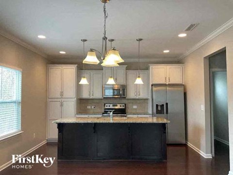 A kitchen with a black countertop and a chandelier hanging from the ceiling.
