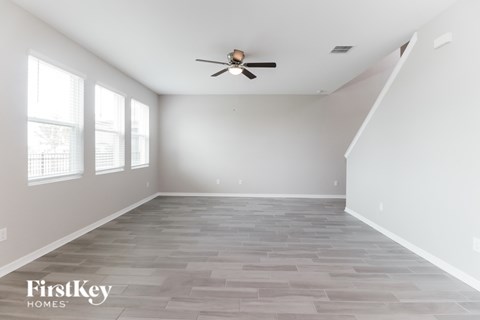 A spacious room with a fan and wooden flooring.