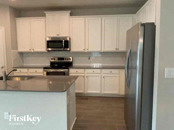 a kitchen with white cabinets and a stainless steel refrigerator