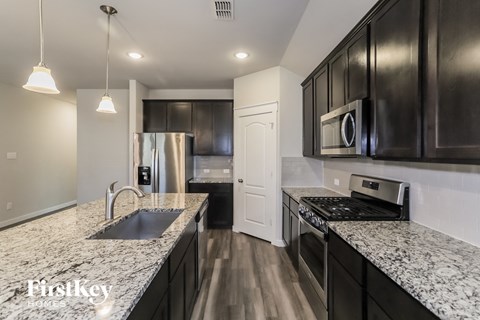 a kitchen with granite counter tops and black cabinets