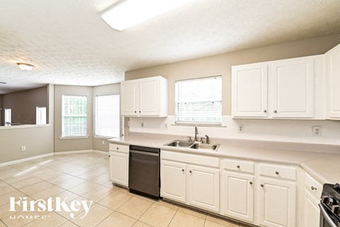 A kitchen with white cabinets and a black dishwasher.
