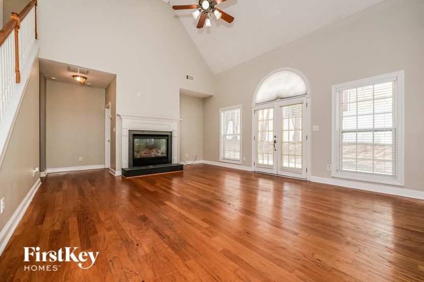 A spacious living room with wood flooring and a fireplace.