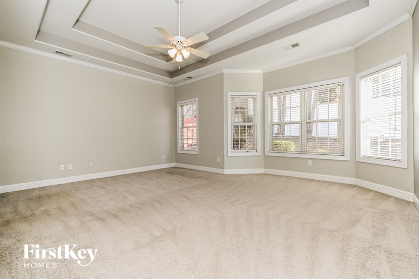 A spacious room with a ceiling fan and carpeted floor.