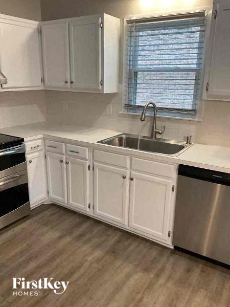 A kitchen with white cabinets and a stainless steel sink.