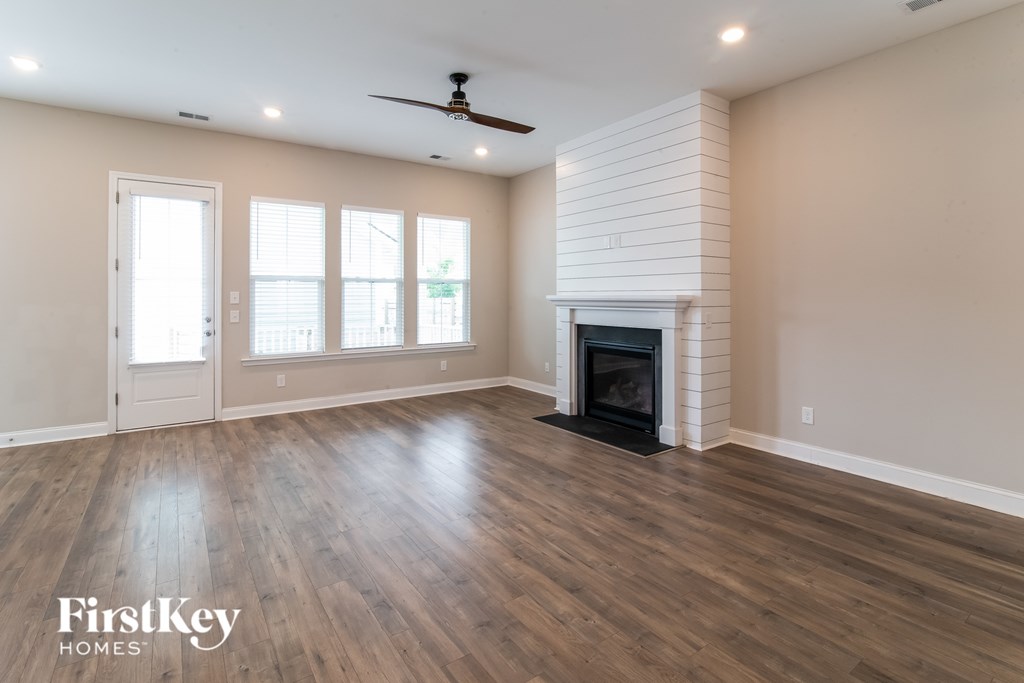 A spacious living room with a fireplace and a ceiling fan.
