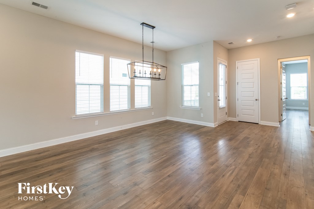 A spacious room with wooden floors and a chandelier hanging from the ceiling.