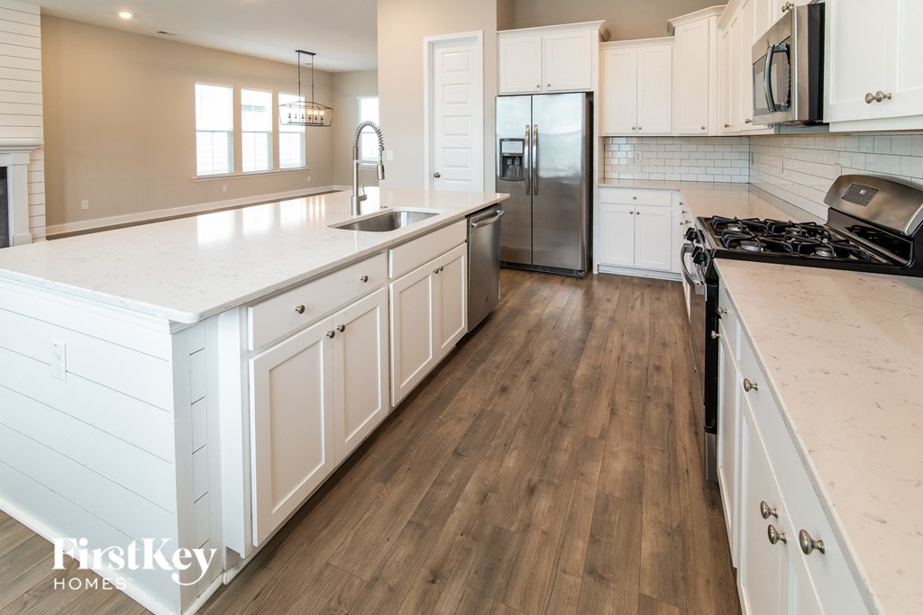 A kitchen with white cabinets and a wooden floor.