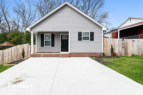 a white house with a driveway and a fence