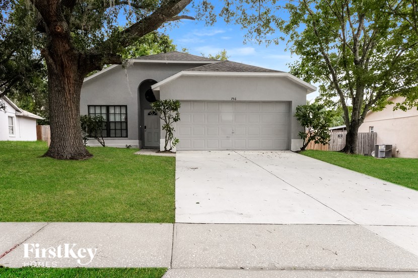 A house with a garage and a tree in front of it.