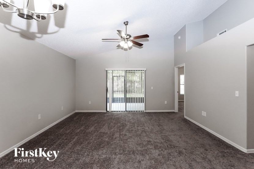 A spacious room with a ceiling fan and a sliding glass door.