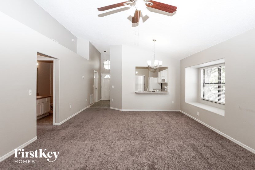 A spacious room with a fan and a chandelier.