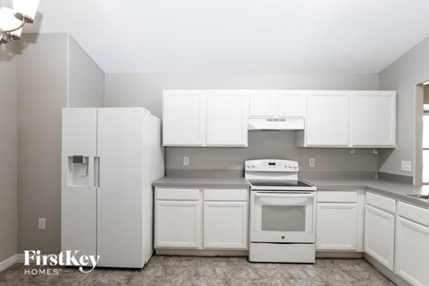 A kitchen with white appliances and cabinets.