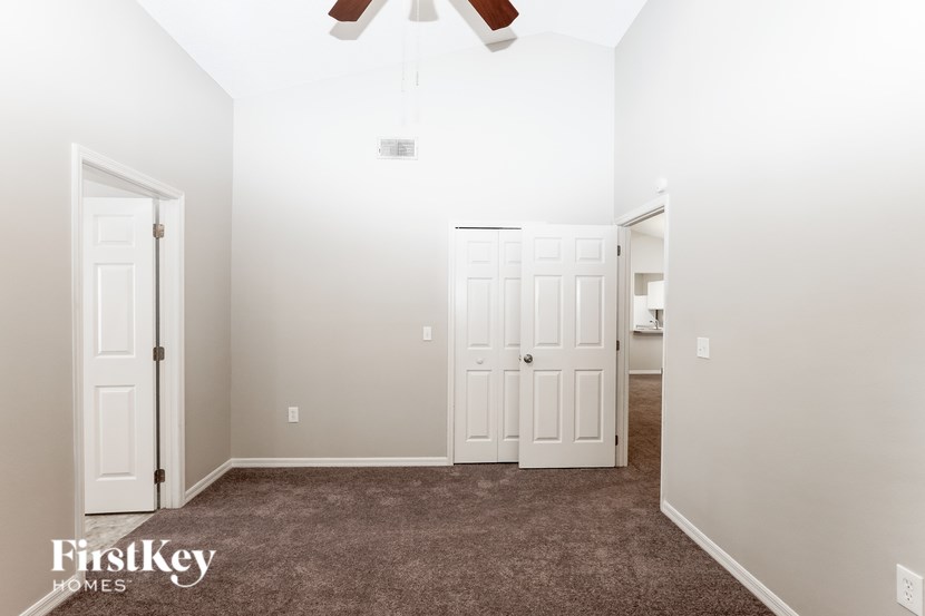 A room with a carpeted floor and a ceiling fan.