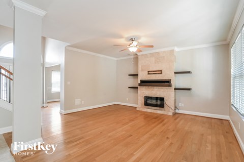 a living room with a fireplace and wooden floors and a ceiling fan