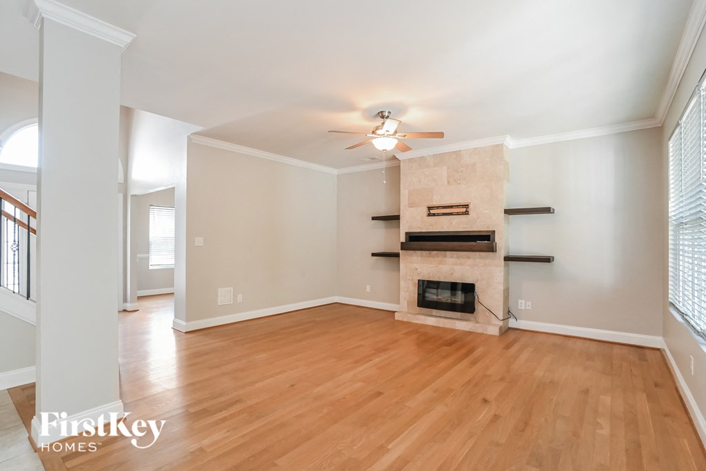 a living room with a fireplace and wooden floors and a ceiling fan