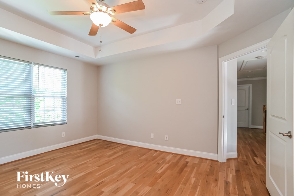 a bedroom with hardwood flooring and a ceiling fan