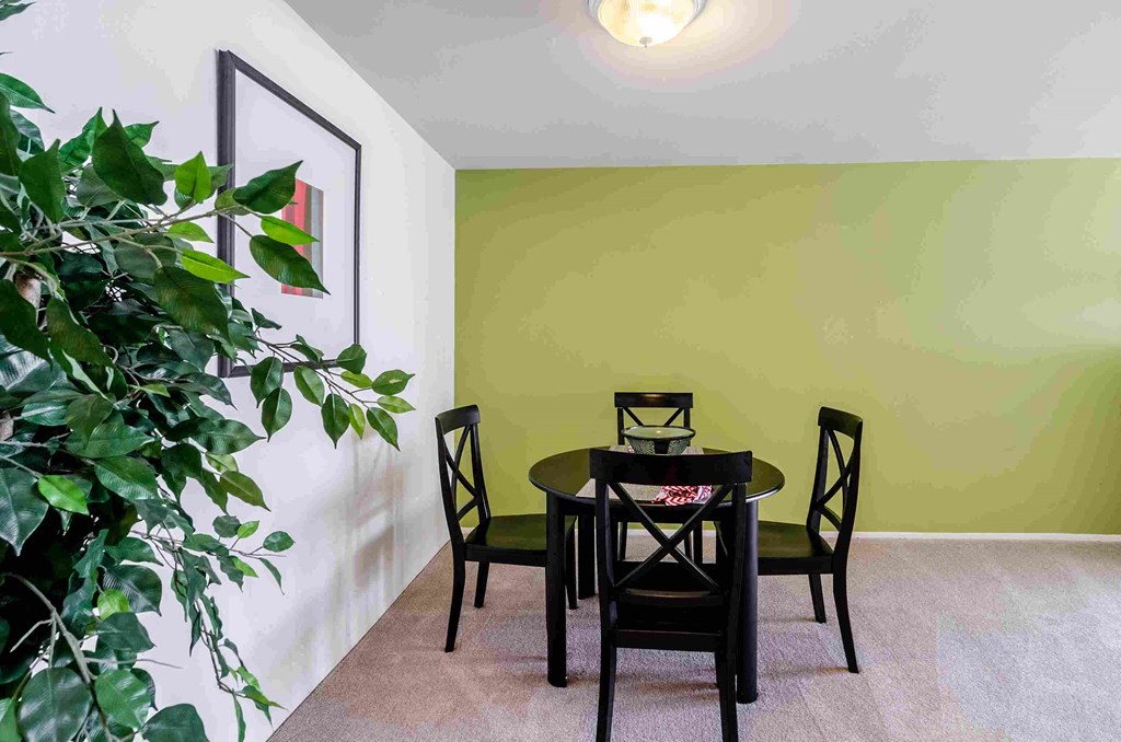 a dining room with a table and chairs and a green wall