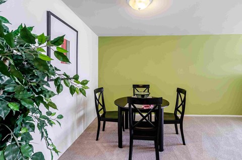 a dining room with a table and chairs and a green wall