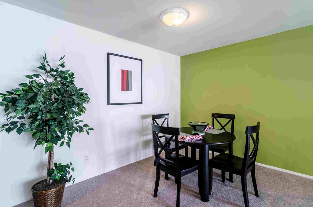 a dining room with a table and chairs and a potted tree
