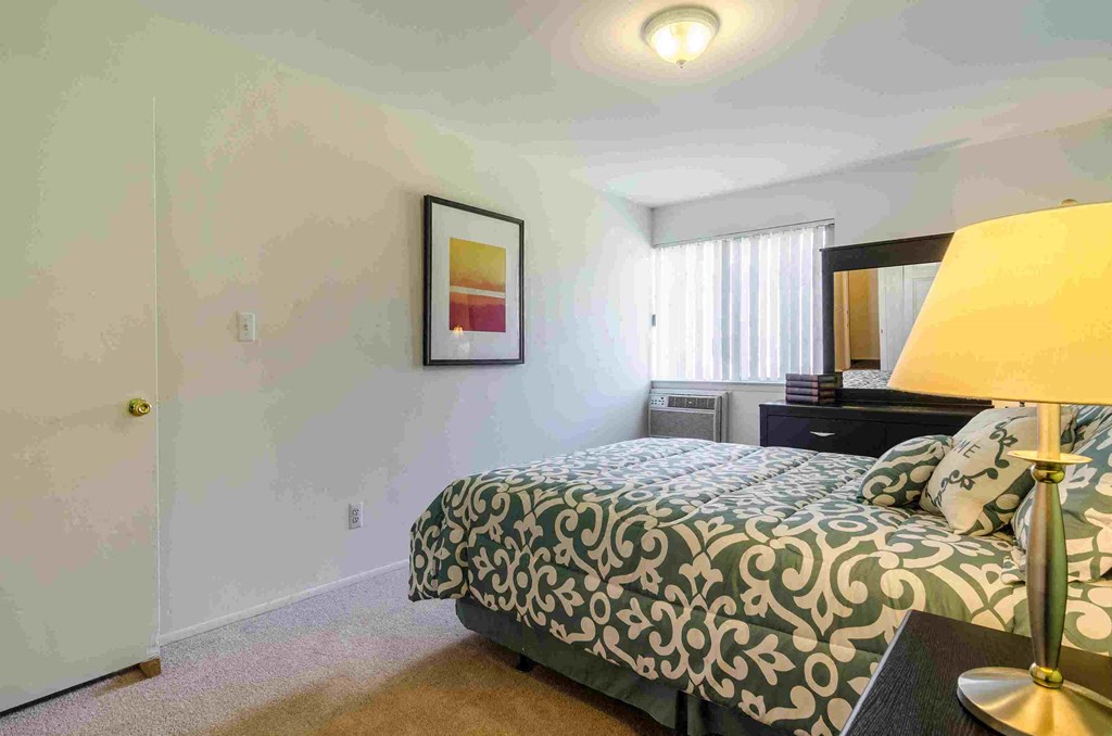 a bedroom with a bed and a desk with a lamp