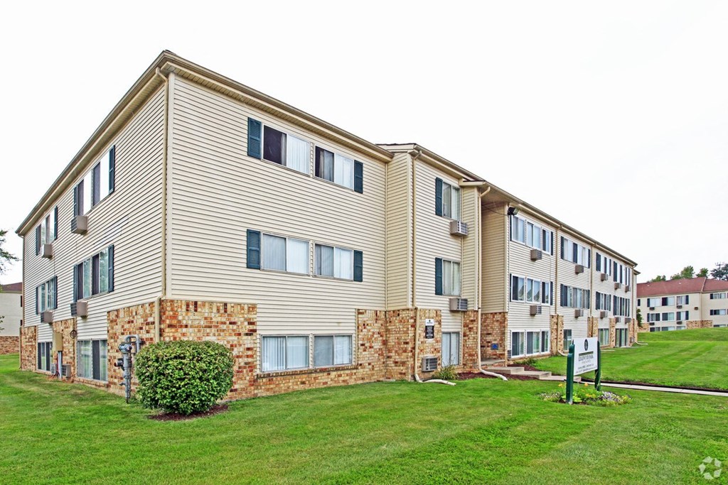 the exterior of an apartment building with a green lawn