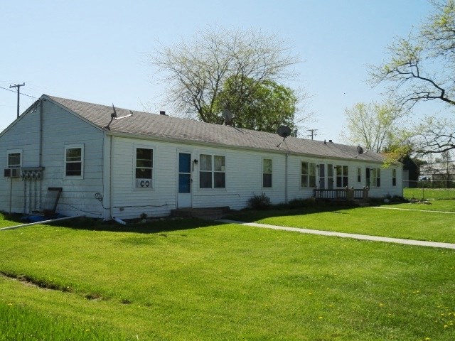 a white house with a green lawn and trees