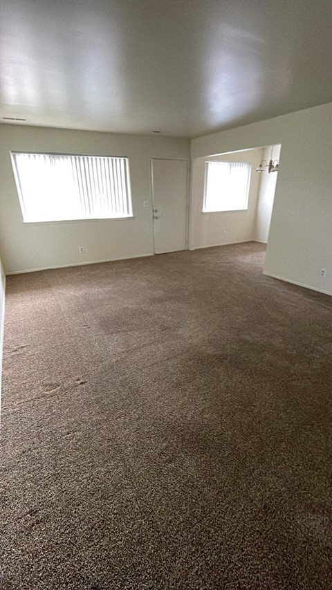 an empty living room with a carpeted floor