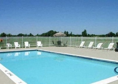 a large swimming pool with white chairs