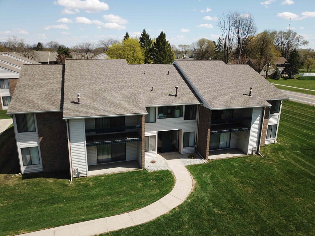 an aerial view of an apartment building with gray roofs