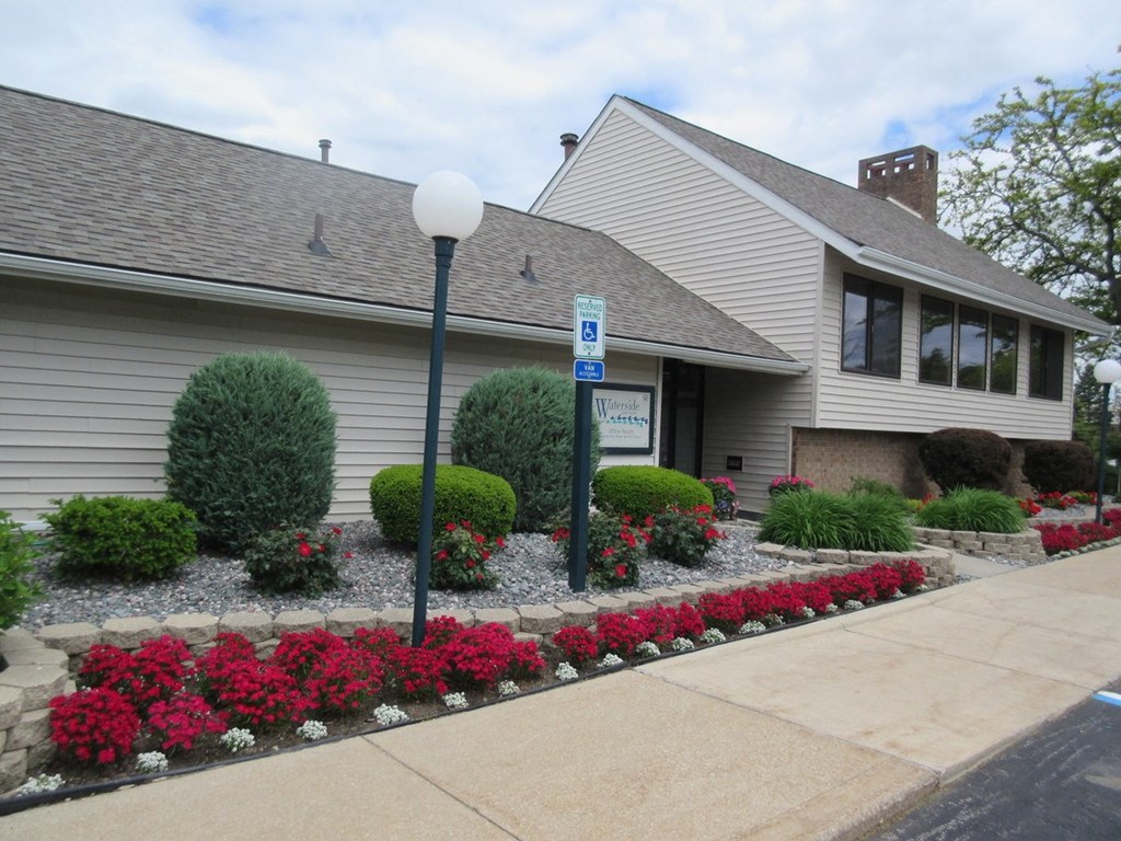 the front of a white house with a landscaped yard