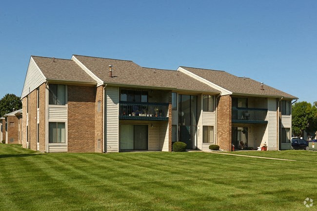 a large apartment building with a green lawn