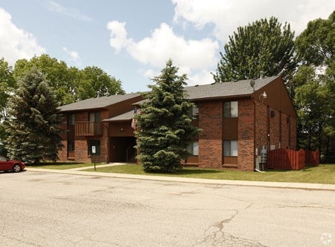 the front of a brick apartment building with a parking lot