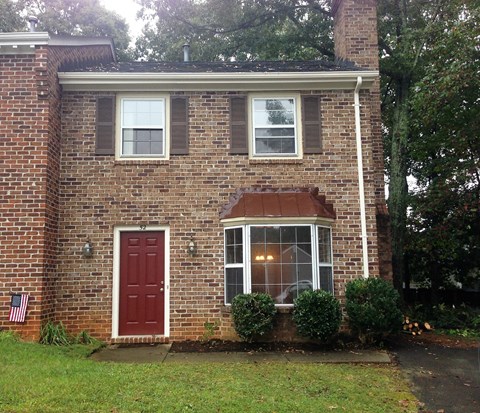 the front of a brick house with a red door