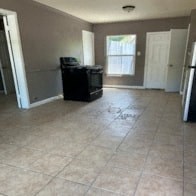 an empty living room with a refrigerator and