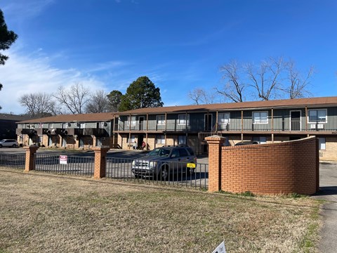 A building with a brown brick wall and a black car parked in front.