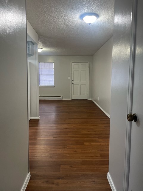 A hallway with wood floors and white walls.
