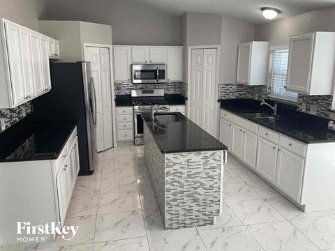a kitchen with white cabinets and black counter tops