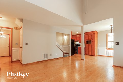 A spacious living room with wooden floors and a staircase leading to the upper level.
