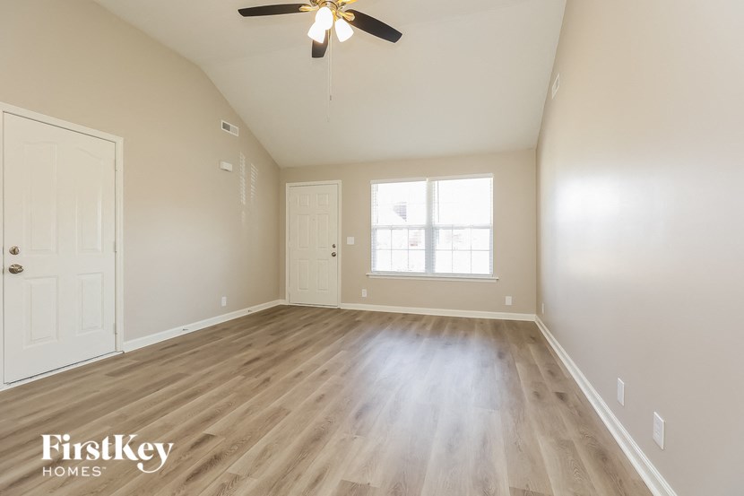 A spacious room with a ceiling fan and wooden flooring.