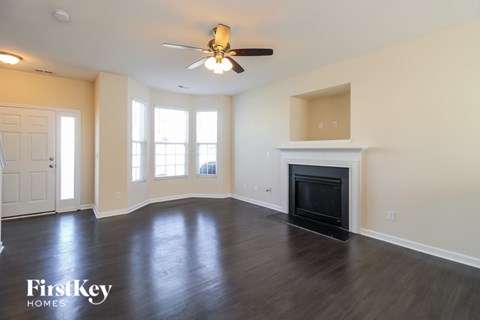 A spacious living room with a fireplace and a ceiling fan.