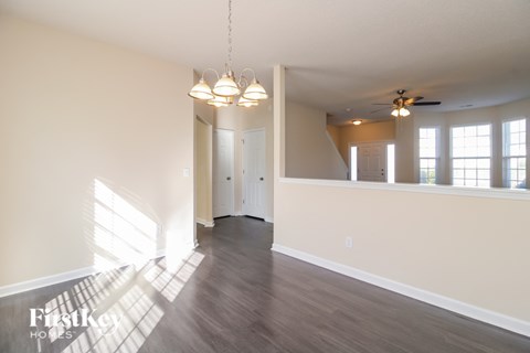 A spacious room with wooden floors and a ceiling fan.